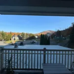 Covered balcony view of parking area and Jiminy Peak summit with fall foliage on surrounding hillsides