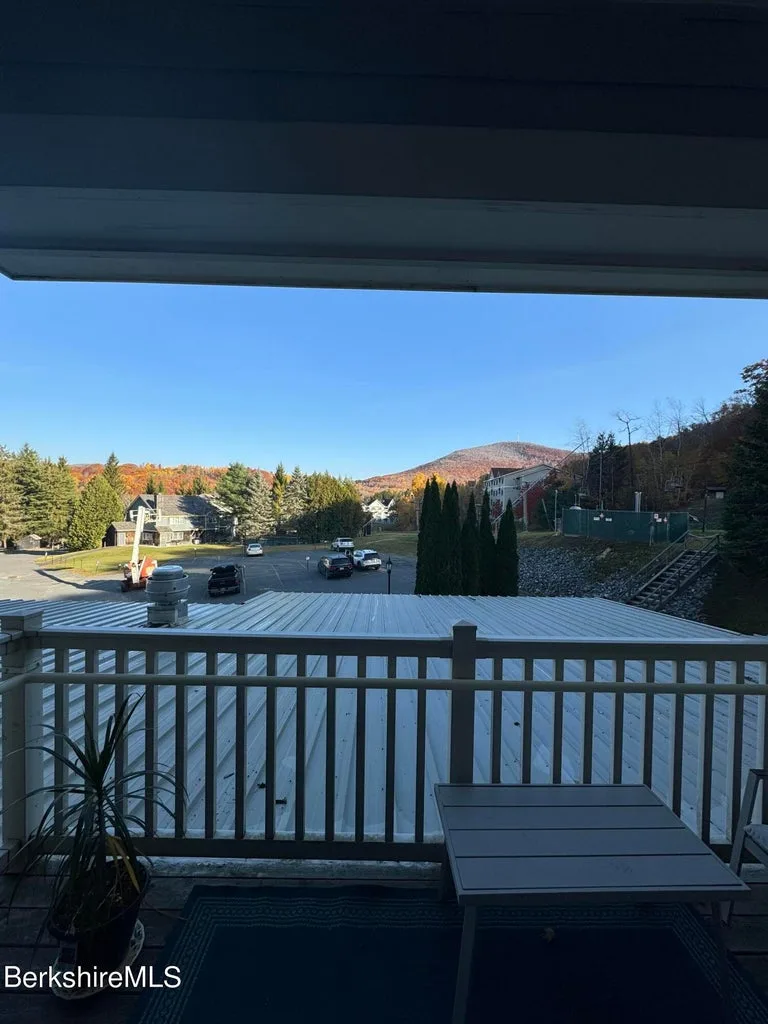 Covered balcony view of parking area and Jiminy Peak summit with fall foliage on surrounding hillsides