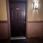 Dark brown entry door marked 862 with wall sconce at JJ's Lodge condominium hallway