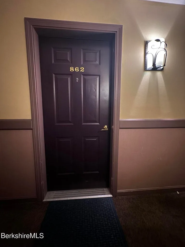 Dark brown entry door marked 862 with wall sconce at JJ's Lodge condominium hallway