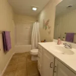 Guest bathroom with tub-shower combo, white vanity, toilet, and butterfly wall decor at JJ's Lodge 862
