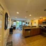 Open kitchen with tile floor, breakfast bar, and stainless dishwasher leading to carpeted living area