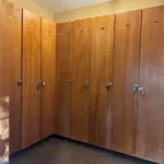 Row of tall wooden ski lockers with padlocks in shared storage room at JJ's Lodge