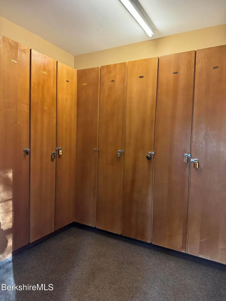 Row of tall wooden ski lockers with padlocks in shared storage room at JJ's Lodge
